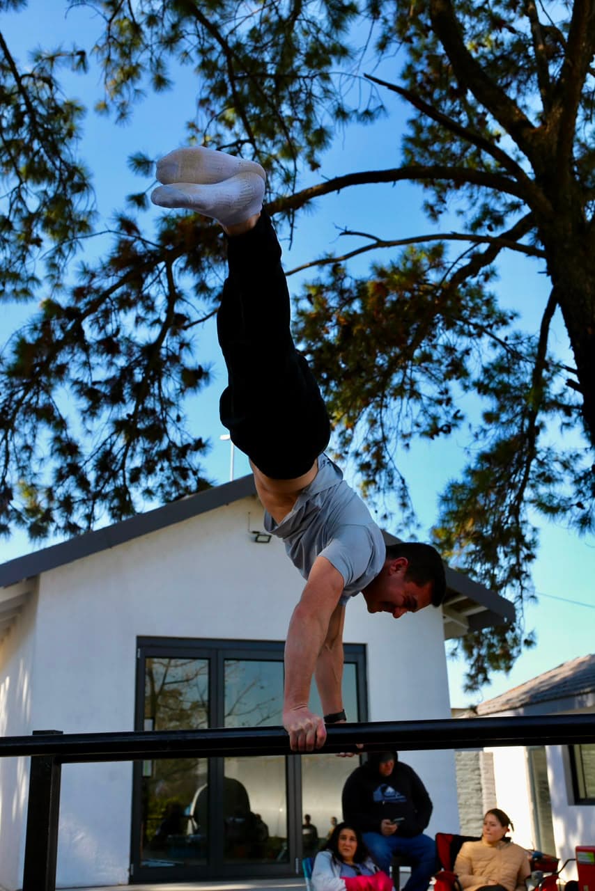 Athlete holding a straight handstand on a bar against open sky at the Elevate Athletic park