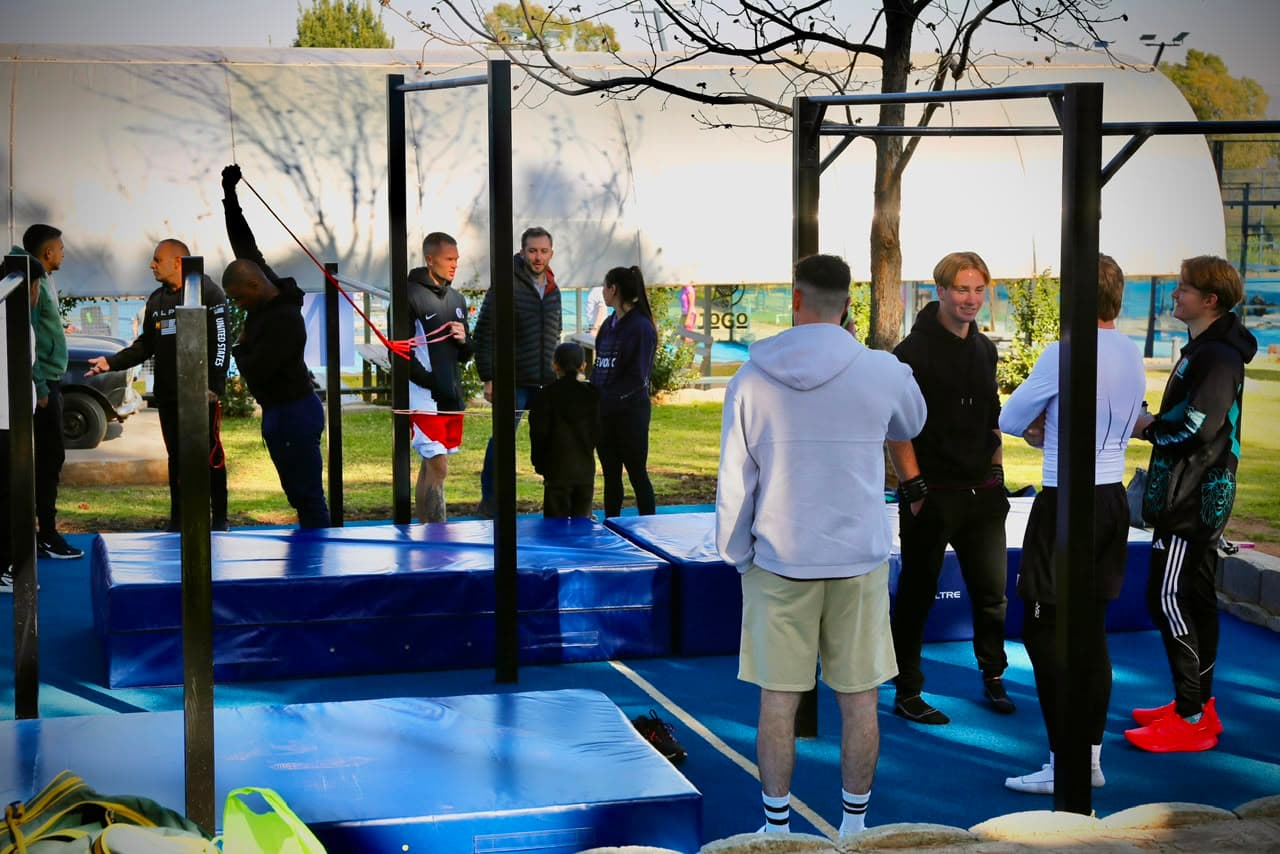 A group class training on the bars and blue matting at the Elevate Athletic park