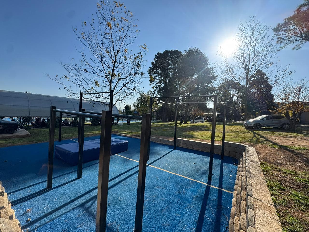 The Elevate Athletic outdoor park in the morning: bars and blue matting under trees and open sky